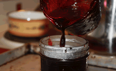 pouring hot blueberry jam into jar